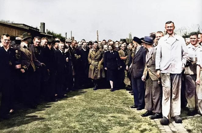 Ingekleurde foto met daarop Rode Kruis-medewerkster Loes van Overeem (midden) die op 7 mei 1945 oorlogscorrespondent Ton van Beers rondleidt in Kamp Amersfoort. De foto siert het omslag van een boekje dat een wandeling van het station naar het kamp beschrijft.